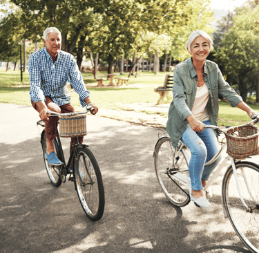an older man and woman riding bicycles in a park