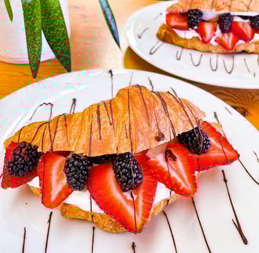 a croissant pastry with fruit on a plate with chocolate sauce