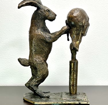 a bronze sculpture of a rabbit carving a human head