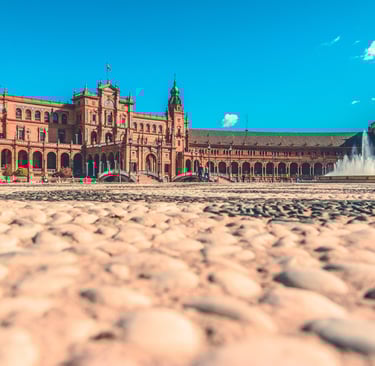 a large building with a fountain in front of a blue sky