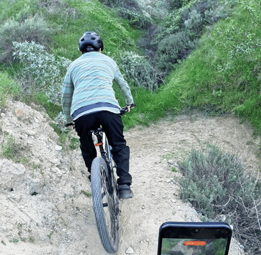 Mountain biker approaching a tight trail switchback at controlled speed before performing a stoppie