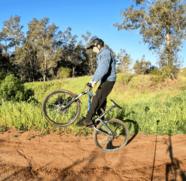 Mountain biker lifting the front wheel and bringing bars close to hips on a J hop