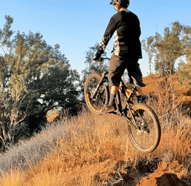 Rider frozen and stiff over a jump, bike flat in the air — showing dead sailor posture
