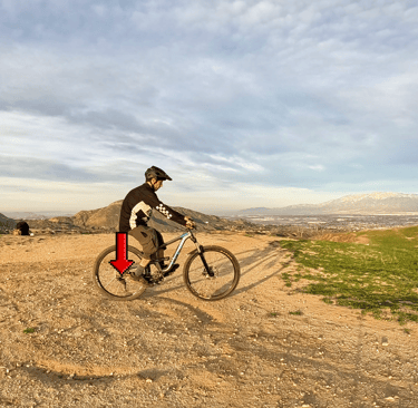 Rider shifting body weight back over rear tire to do a rear wheel lift