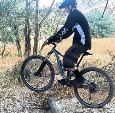 mountain bike rider lifting front wheel using downward pedal stroke during wheelie drop