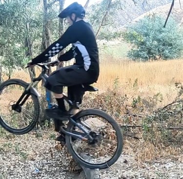 mountain biker in mid wheelie drop keeping finger on rear brake and body centered