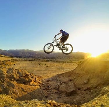 Mountain biker hitting a canyon gap jump at sunrise, showcasing advanced freeride technique