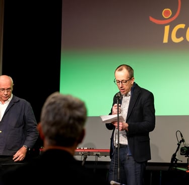 Un homme en veste noire un micro à la main