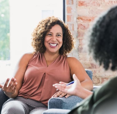 a woman sitting on a couch talking to another woman