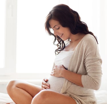 a pregnant woman sitting on a bed with her belly in her belly