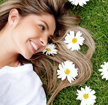 woman laying in the grass with daises beside her