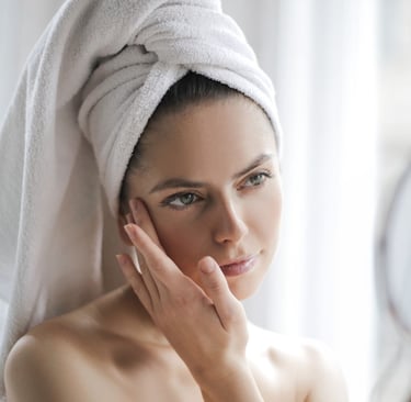 a woman with a towel wrapped around her head looking in a hand held mirror