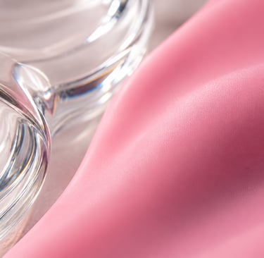 Close-up of soft pink silk fabric draped next to elegant curved borosilicate glass