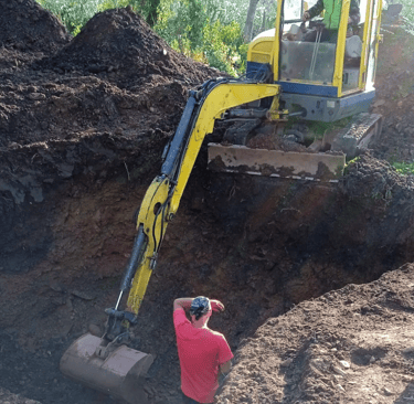 Excavator digging natural pool under expert supervision during Aqua Vitae construction phase