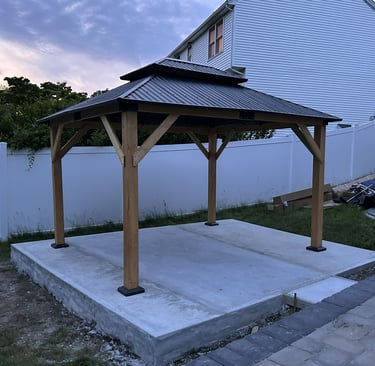 A recently-assembled wooden gazebo with a two-tiered metal roof.