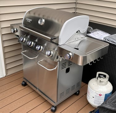 Left side view of stainless steel propane grill showing side burner and hooks