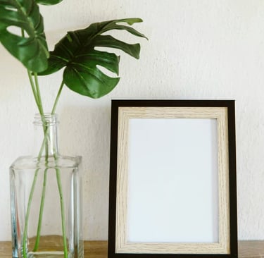 Empty picture frame with plant in vase beside it symbolizing perspective, everyday essentials