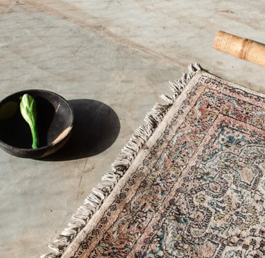 Close-up of yoga mat with bowl holding cactus flower in afternoon sunlight, everyday essentials