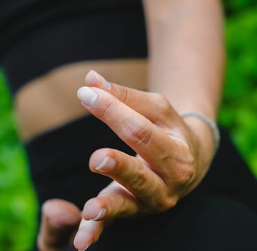 Close-up of fingers in meditation mudra before lush green background, guided meditation