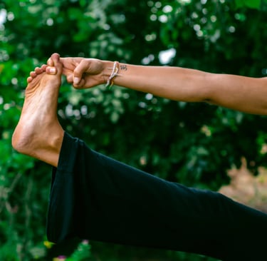 Close-up of yoga pose holding big toe with Om tattoo and blessing band, mindful essentials