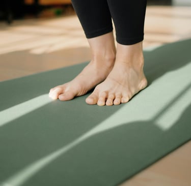 Close-up of feet on green yoga mat in afternoon sun, symbolizing yoga philosophy and psychology beyond the mat in daily life.