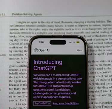 A mobile over a book, in the mobile's display an app ChatGPT is displaying.