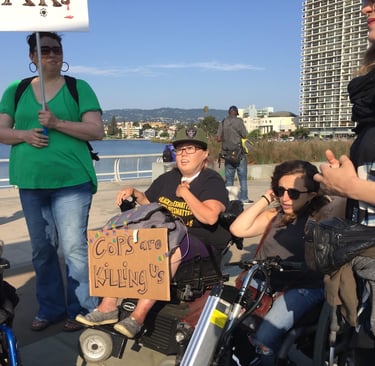 Photo of Stacey with friends at a protest with a sign saying "cops are killing us"