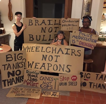 Photo of Stacey with Friends displaying posters they made in protest of Urban Shield and supporting BLM.