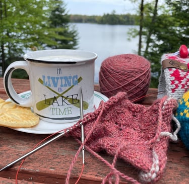 Latte and knitting project sitting next to a lake