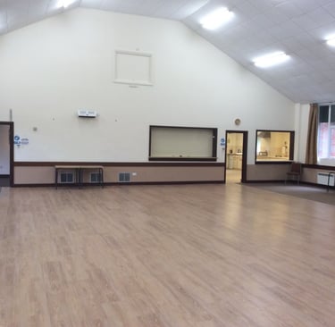 a large village hall room with a wooden floor