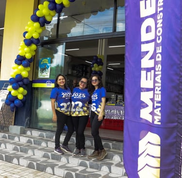 foto de colaboradores, em segundo plano, na frente da loja, bandeira com logo, em primeiro plano.