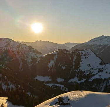 A panoramic view of sun-drenched, snow-covered mountain peaks and ski runs from a high alpine statio