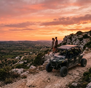Couple beside off-road buggy on rocky ridge with panoramic Valle d'Itria sunset view