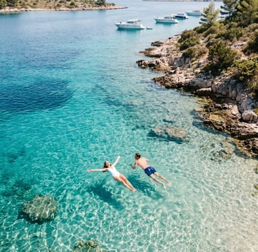 Couple floating in crystal clear turquoise Blue Lagoon near Split, aerial drone view