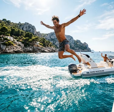  Excited man jumping from white speedboat into crystal turquoise Adriatic with rocky cliffs