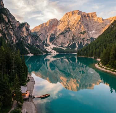 Aerial view of turquoise Lake Braies reflecting Dolomite peaks at golden hour