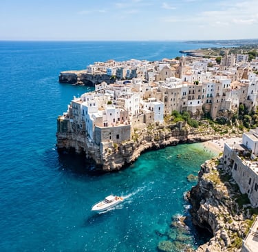 Aerial view of Polignano a Mare white clifftop town with private boat on turquoise sea