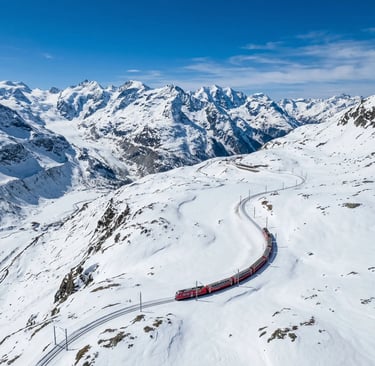 Aerial view of red Bernina Express winding through snow-covered Swiss Alpine landscape