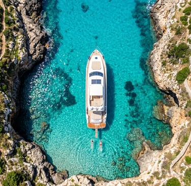 Aerial view of private luxury boat anchored in turquoise cove with swimmers, Puglia Italy