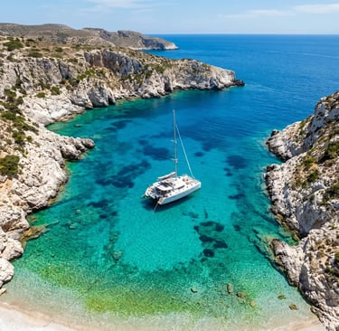 Aerial view of luxury catamaran anchored in Polyegos turquoise cove near Milos, Greece 