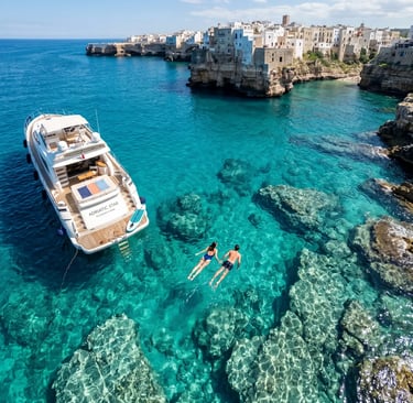 Couple swimming beside luxury private yacht in turquoise water near Polignano a Mare, Puglia