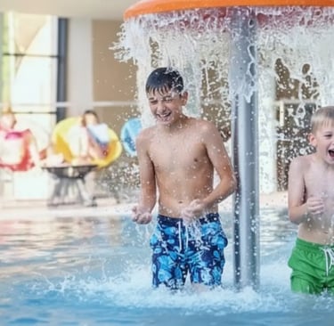 A young boy playing under a water fountain in the family pool area at Aqua Dome, a top-tier luxury w