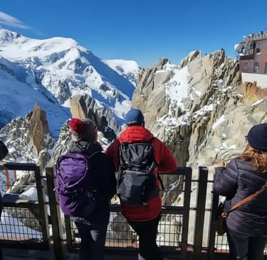 Tourists enjoying panoramic views of the French Alps from the Aiguille du Midi terrace on a Chamonix