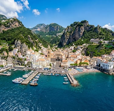 Aerial view of Amalfi cathedral and waterfront harbor with turquoise Mediterranean water