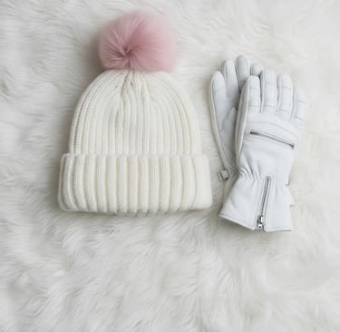 Cute winter ski fashion flat lay with a white hat featuring a pink pom-pom and matching white gloves