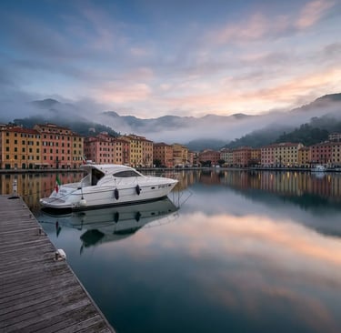 Private boat moored at La Spezia harbor at dawn with misty hills in the background