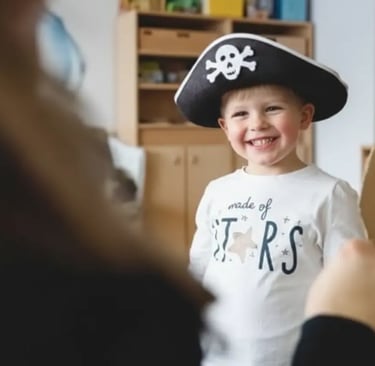 A young boy smiling while wearing a pirate hat during an indoor creative workshop at a family resort