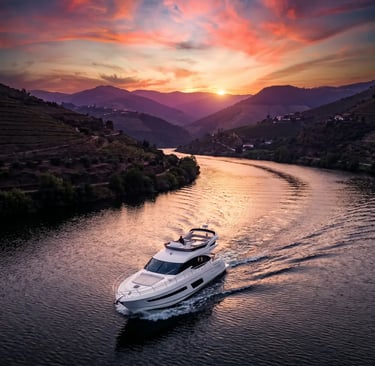 Luxury yacht cruising Douro River at dramatic sunset with pink sky and mountain silhouettes