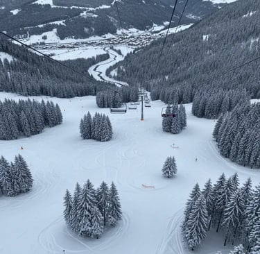 Aerial view of a snow-covered ski slope, evergreen forests, and a mountain village in a valley under