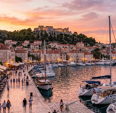 Hvar Town harbor at golden hour with Spanish Fortress and sailboats on island tour